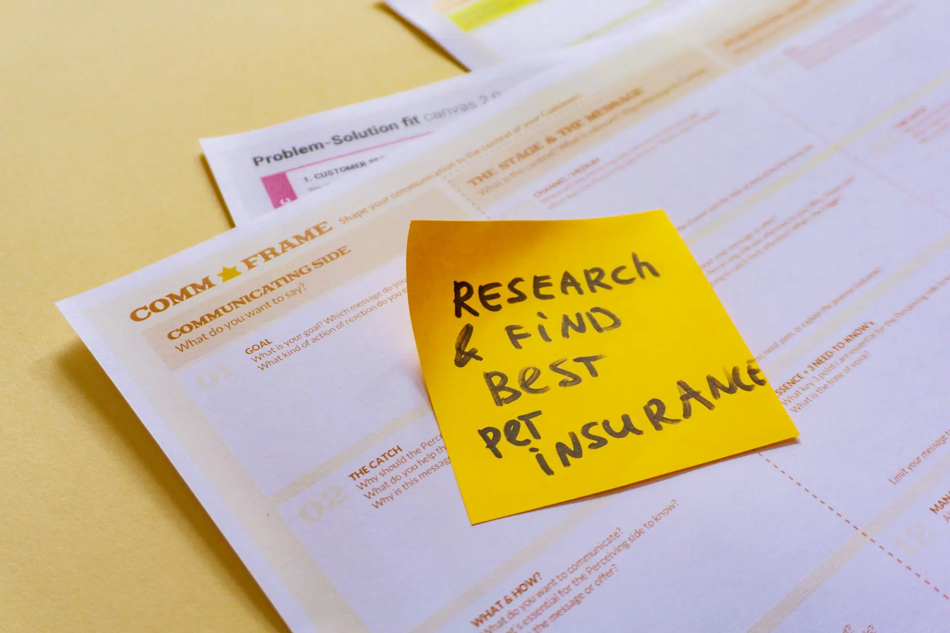 There is a yellow sticky note on a piece of paper that says, "research & find best pet insurance."